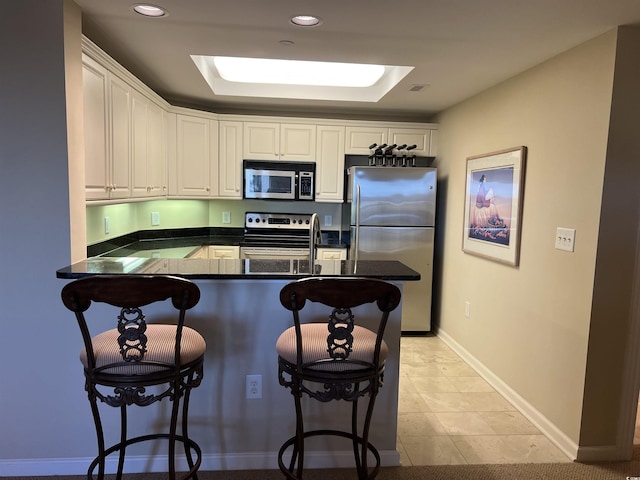 kitchen with kitchen peninsula, stainless steel appliances, and white cabinetry