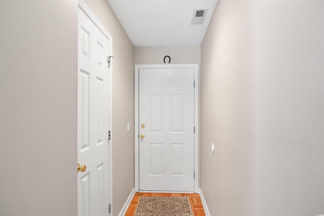 doorway with a textured ceiling and light hardwood / wood-style floors