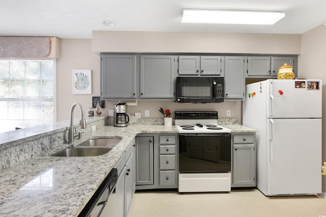 kitchen with light stone countertops, white appliances, gray cabinetry, and sink