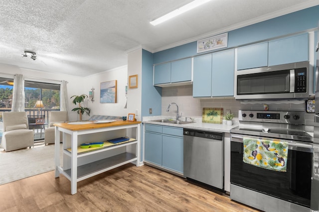 kitchen with blue cabinetry, appliances with stainless steel finishes, light wood-type flooring, and sink