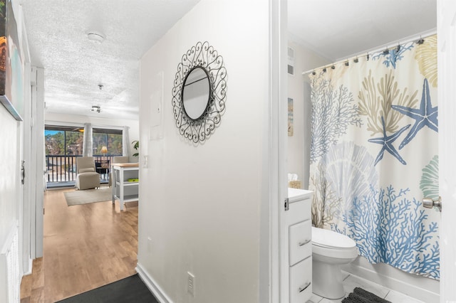 full bathroom with a textured ceiling, toilet, vanity, shower / tub combo, and hardwood / wood-style flooring