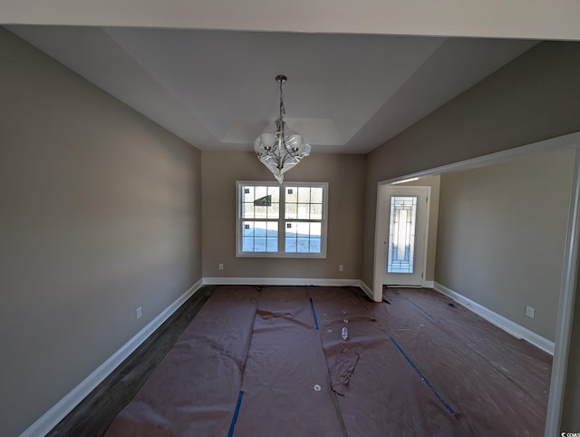 unfurnished dining area with a tray ceiling and a notable chandelier