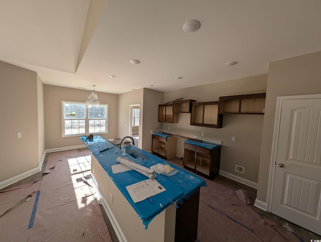 kitchen with a chandelier, an island with sink, decorative light fixtures, and sink