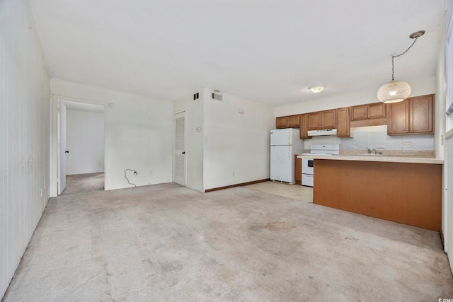 kitchen featuring decorative light fixtures, light colored carpet, white appliances, and kitchen peninsula