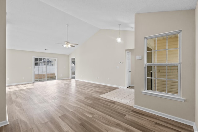 unfurnished living room featuring ceiling fan, light wood-type flooring, and vaulted ceiling