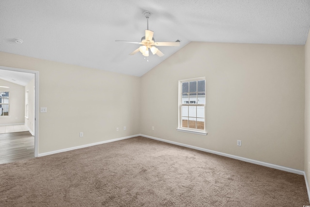 carpeted empty room featuring a wealth of natural light, ceiling fan, and vaulted ceiling