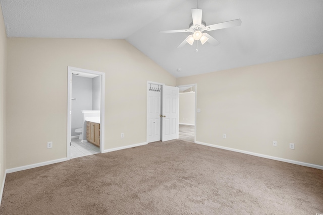 unfurnished bedroom with connected bathroom, light colored carpet, ceiling fan, and lofted ceiling