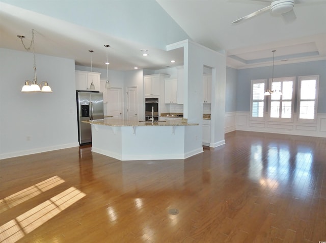 kitchen featuring a breakfast bar, stainless steel appliances, a spacious island, decorative light fixtures, and white cabinetry