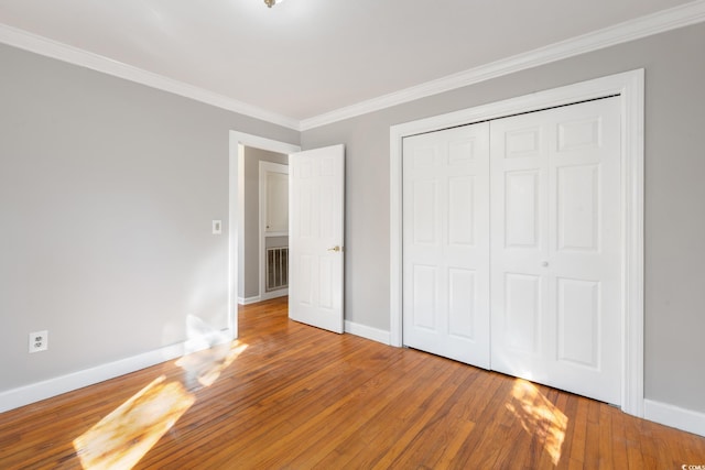 unfurnished bedroom featuring a closet, ornamental molding, and hardwood / wood-style flooring