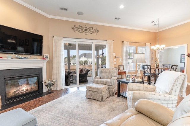 living room with hardwood / wood-style floors, an inviting chandelier, and ornamental molding