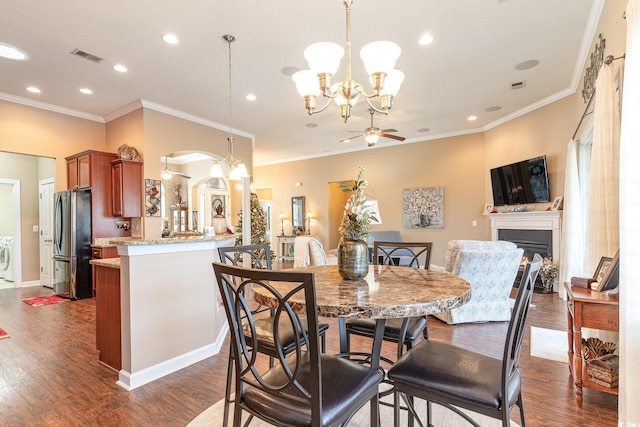 dining space featuring ceiling fan with notable chandelier, dark wood-type flooring, and crown molding