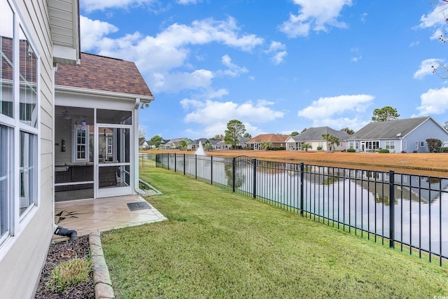 view of yard with a sunroom and a water view