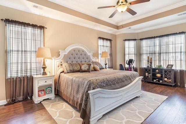 bedroom with ceiling fan, crown molding, dark wood-type flooring, and a tray ceiling