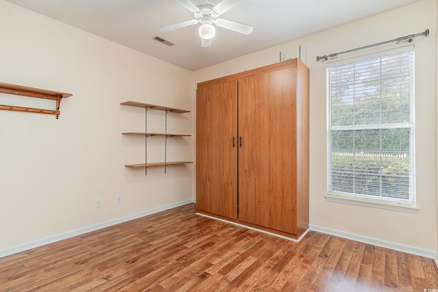 unfurnished bedroom with ceiling fan, a closet, light hardwood / wood-style flooring, and multiple windows