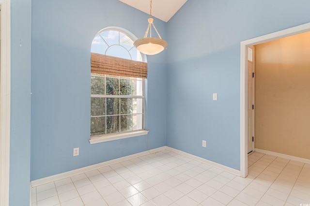 empty room with lofted ceiling and light tile patterned floors