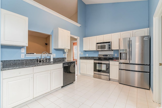 kitchen featuring high vaulted ceiling, dark stone counters, sink, appliances with stainless steel finishes, and white cabinetry