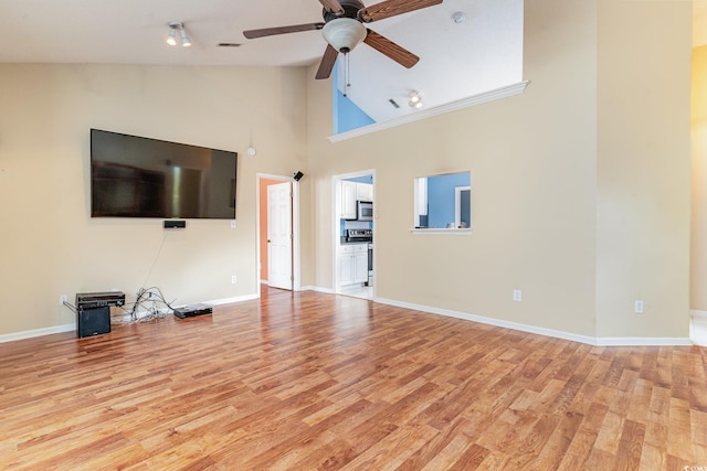 unfurnished living room with ceiling fan, light wood-type flooring, and high vaulted ceiling