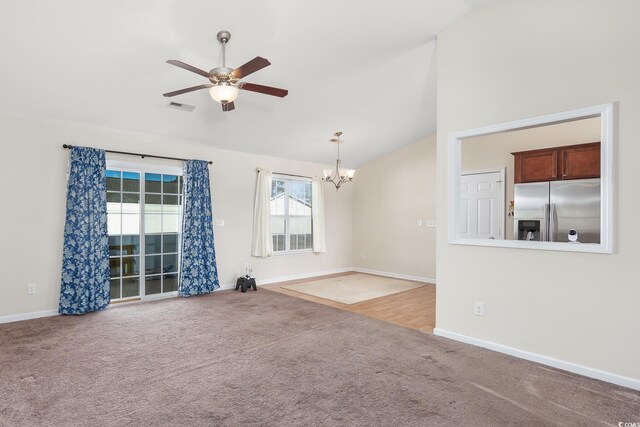 unfurnished living room with carpet flooring, lofted ceiling, and ceiling fan with notable chandelier