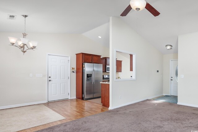 unfurnished living room with high vaulted ceiling, light colored carpet, and ceiling fan with notable chandelier