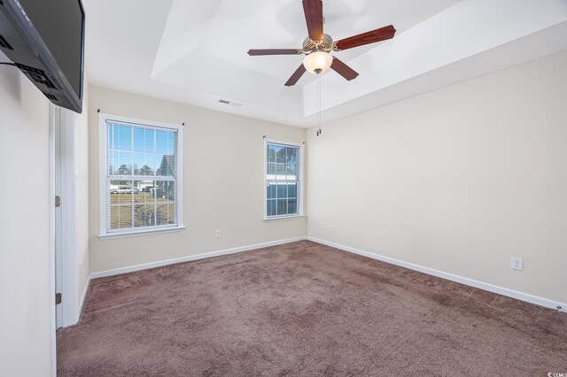 carpeted spare room featuring ceiling fan and a tray ceiling