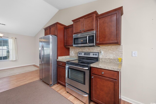 kitchen featuring lofted ceiling, decorative backsplash, appliances with stainless steel finishes, and light hardwood / wood-style flooring