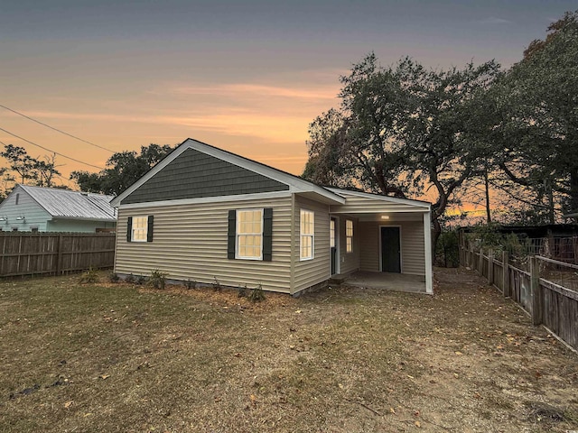 back house at dusk with a patio area and a yard