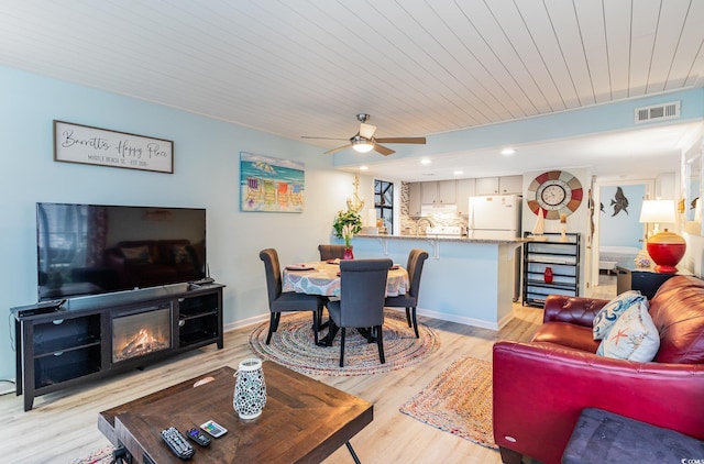 living room featuring a fireplace, light hardwood / wood-style floors, and ceiling fan