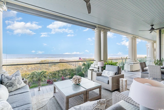 view of patio featuring an outdoor living space, ceiling fan, a water view, and a beach view