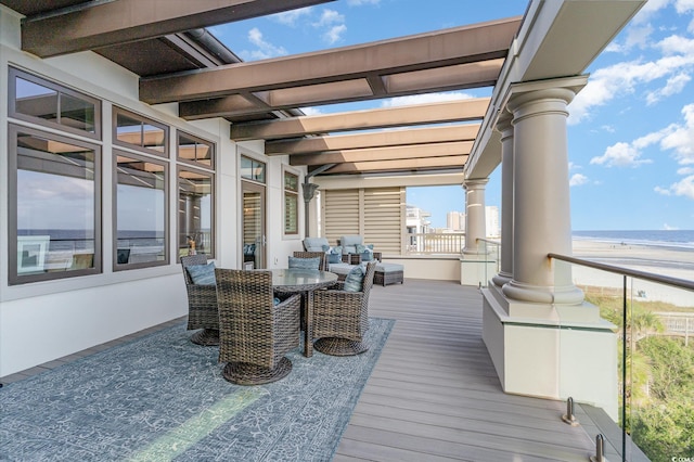 wooden terrace featuring a water view and a beach view