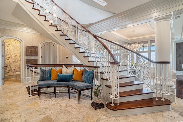 stairway with ornate columns, crown molding, and a chandelier