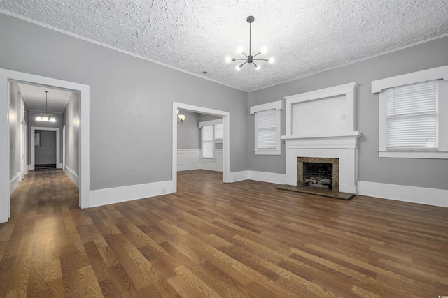 unfurnished living room with a notable chandelier, dark wood-type flooring, crown molding, and a textured ceiling