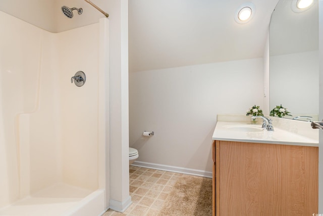 bathroom with a stall shower, toilet, vanity, baseboards, and vaulted ceiling