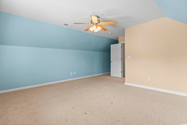 additional living space with vaulted ceiling, light colored carpet, a ceiling fan, and baseboards