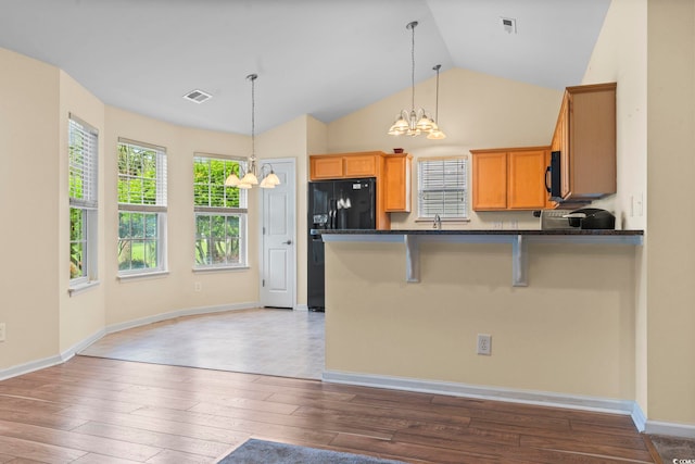 kitchen featuring a chandelier, black appliances, dark countertops, hardwood / wood-style floors, and lofted ceiling