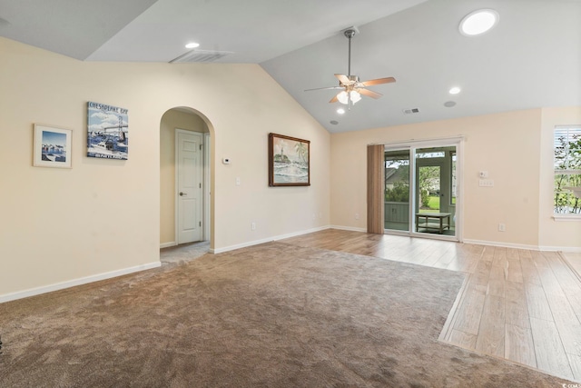 spare room with ceiling fan, lofted ceiling, arched walkways, baseboards, and light wood-style floors