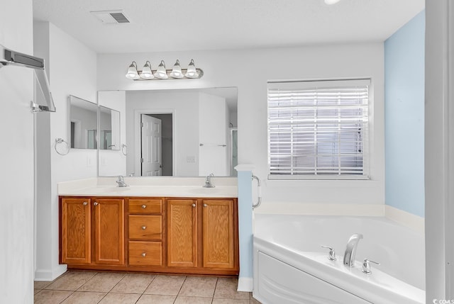 bathroom with a textured ceiling, vanity, tile patterned floors, and a bathing tub