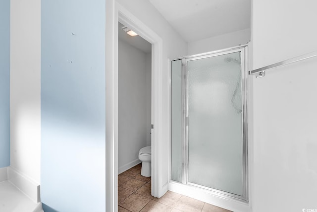 bathroom with tile patterned flooring, toilet, and an enclosed shower