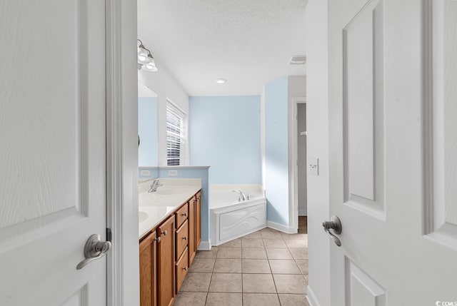 bathroom with tile patterned flooring, a textured ceiling, vanity, and a tub to relax in