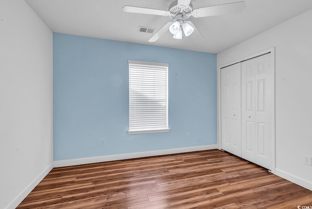 unfurnished bedroom with dark hardwood / wood-style floors, ceiling fan, a textured ceiling, and a closet