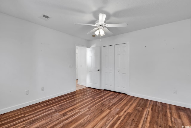 unfurnished bedroom with a closet, ceiling fan, dark hardwood / wood-style flooring, and a textured ceiling