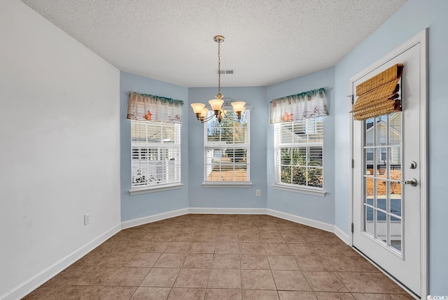 unfurnished dining area with light tile patterned floors, a textured ceiling, and an inviting chandelier