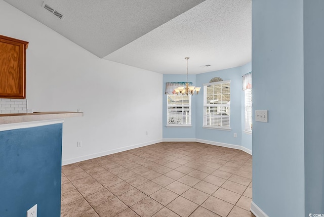 unfurnished dining area featuring light tile patterned flooring, a textured ceiling, and a chandelier