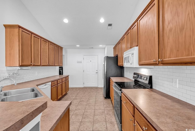 kitchen featuring sink, vaulted ceiling, decorative backsplash, light tile patterned floors, and stainless steel appliances