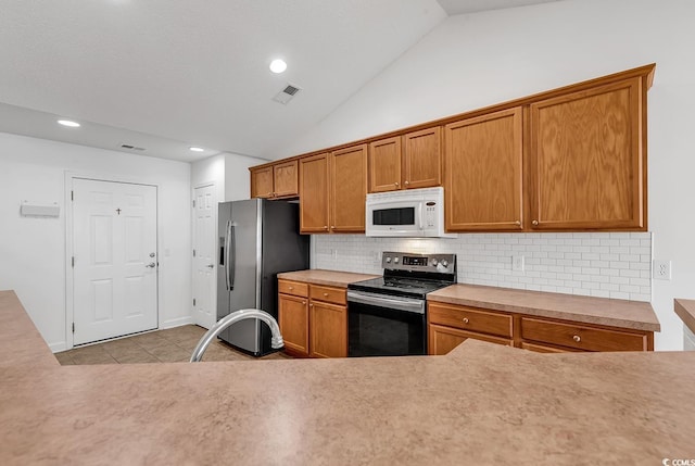 kitchen featuring decorative backsplash, light tile patterned floors, stainless steel appliances, and lofted ceiling