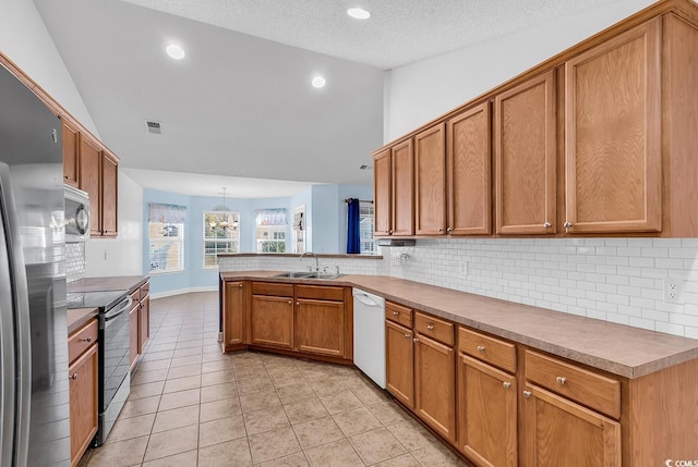 kitchen with sink, a textured ceiling, appliances with stainless steel finishes, decorative light fixtures, and kitchen peninsula