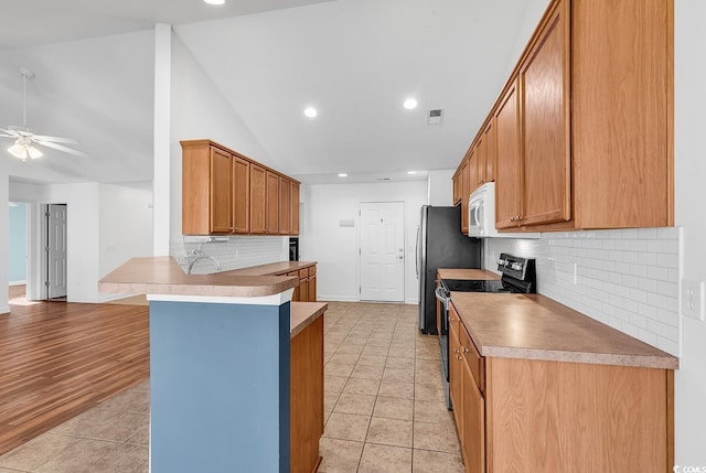 kitchen featuring light hardwood / wood-style flooring, ceiling fan, stainless steel electric range oven, tasteful backsplash, and kitchen peninsula