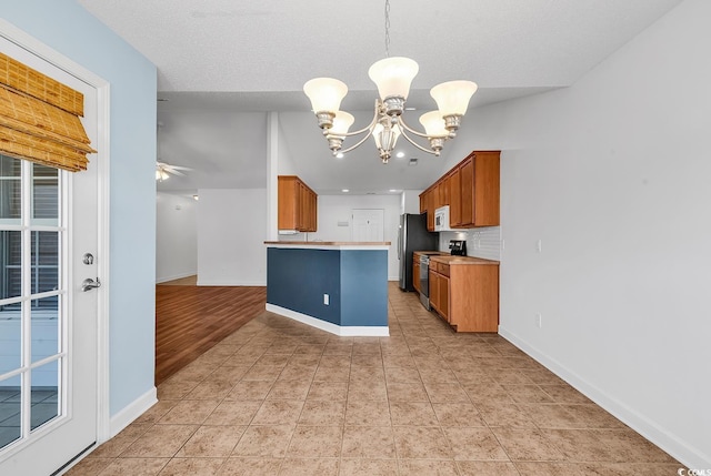 kitchen with hanging light fixtures, ceiling fan with notable chandelier, stainless steel range with electric stovetop, and lofted ceiling