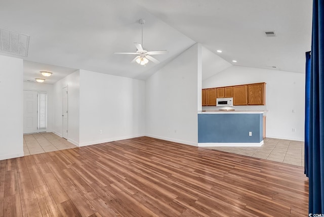 unfurnished living room featuring light wood-type flooring, vaulted ceiling, and ceiling fan