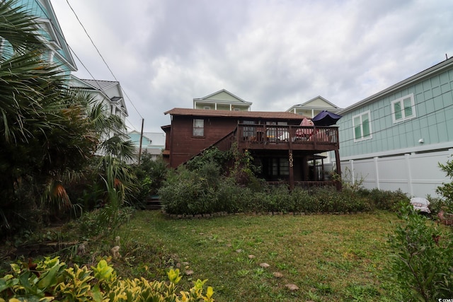 back of property with a deck and a lawn