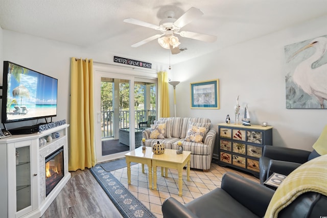 living room featuring light wood-type flooring, a textured ceiling, and ceiling fan